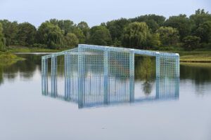 Floating blue structure over a body of water. The material looks like "breeze blocks" popular in tropical construction.