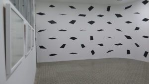 Black prisms or planes decorate a white wall
