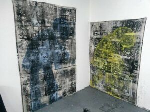 Two Fernando Pintando paintings side by side, one with a blue figure and one with a yellow figure.
