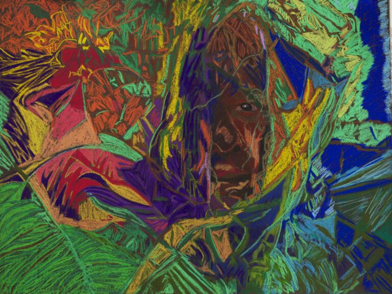 A man is hiding behind vibrant leaves and red flowers.