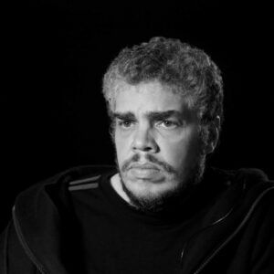 Black and white photo of the artist, looking serious.