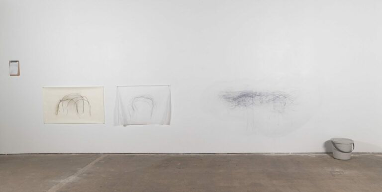 Graphite on paper and the wall drawn by the artist placing her back to the wall and moving.