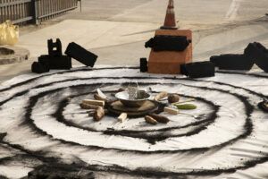 Tubers placed around a bowl with a cheese grater. Surrounding this, there are consecutive rings of charcoal and bricks made of charcoal.