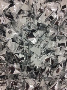 Silver candy wrappers with black logos and writing on it.