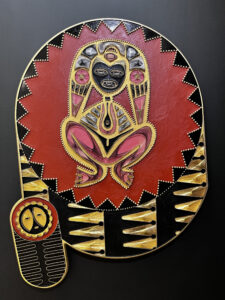 "Here, we encounter a sculpture of the ancestral mother Atabey, constructed using hammered nails." - Glendalys Medina. The goddess figure sits in the middle of a red star shape surrounded by a black trim.