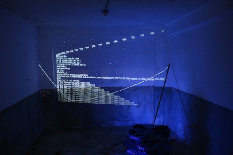 White emotional text on a blue wall projection mimics the blue tarps seen after Maria.