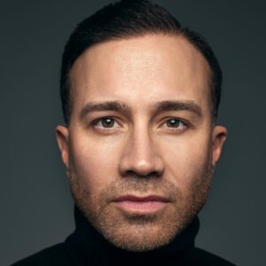 A very close up photo of artist César Abreu. He looks into the camera with a neutral expression.