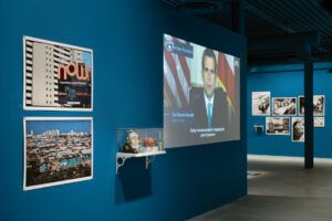 Inside the Museum of the Old Colony, installation walls are a dark blue. Pablo Delano's work is displayed on the walls.