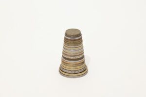 Stack of assorted currency coins from largest at the base to smallest at the top. The coins sit on a white background.