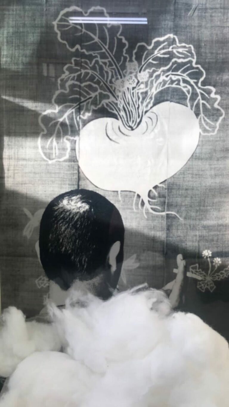 It’s a mural size silver gelatin photograph from an original negative of a man facing away from the camera and towards a painting. He is smoking.