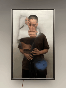 Distorted self-portrait of the artist in the mirror. Their face is morphed into four squished-together faces. Their body remains mostly untouched.