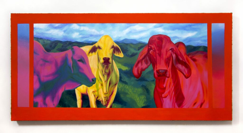 Three cows painted in bright colors in front of a sprawling green landscape.