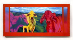 Three cows painted in bright colors in front of a sprawling green landscape.
