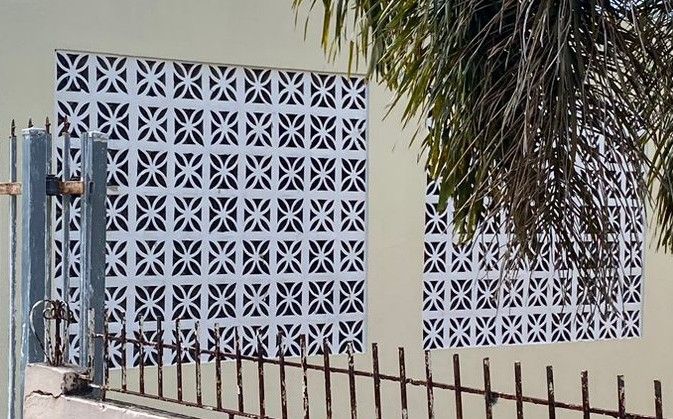 Breeze blacks built into a clean white wall. palm trees dip into the frame.