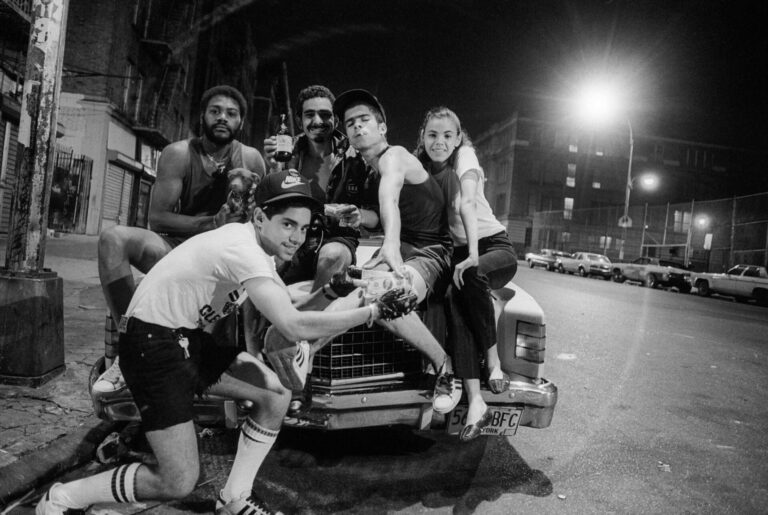 Friends hanging out on a car at night.