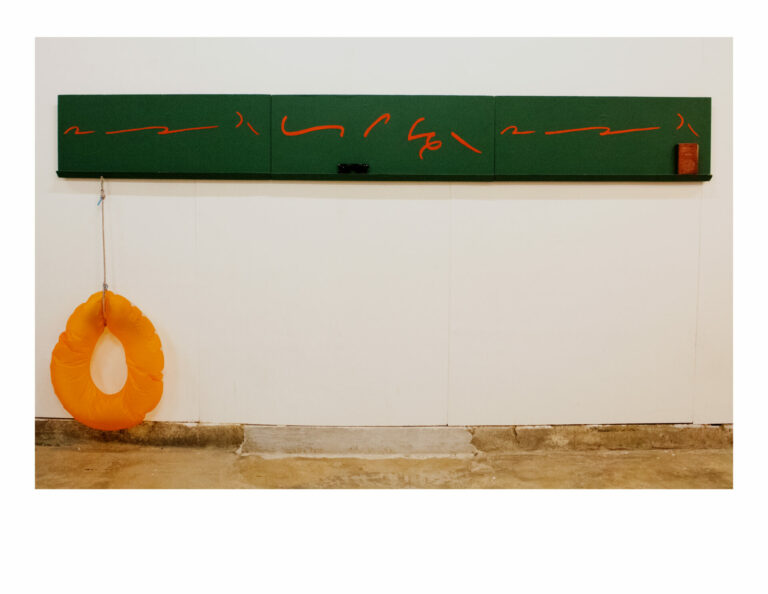 Red shorthand written on green chalkboard. Connected to the board is a hanging orange floatation ring.