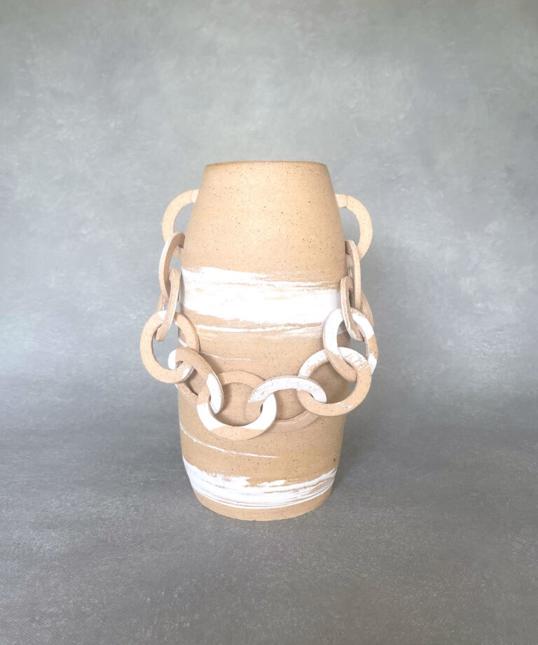 A tan-colored vase with white brushstrokes on the sides. A chain link connects the left and right side of the vase.