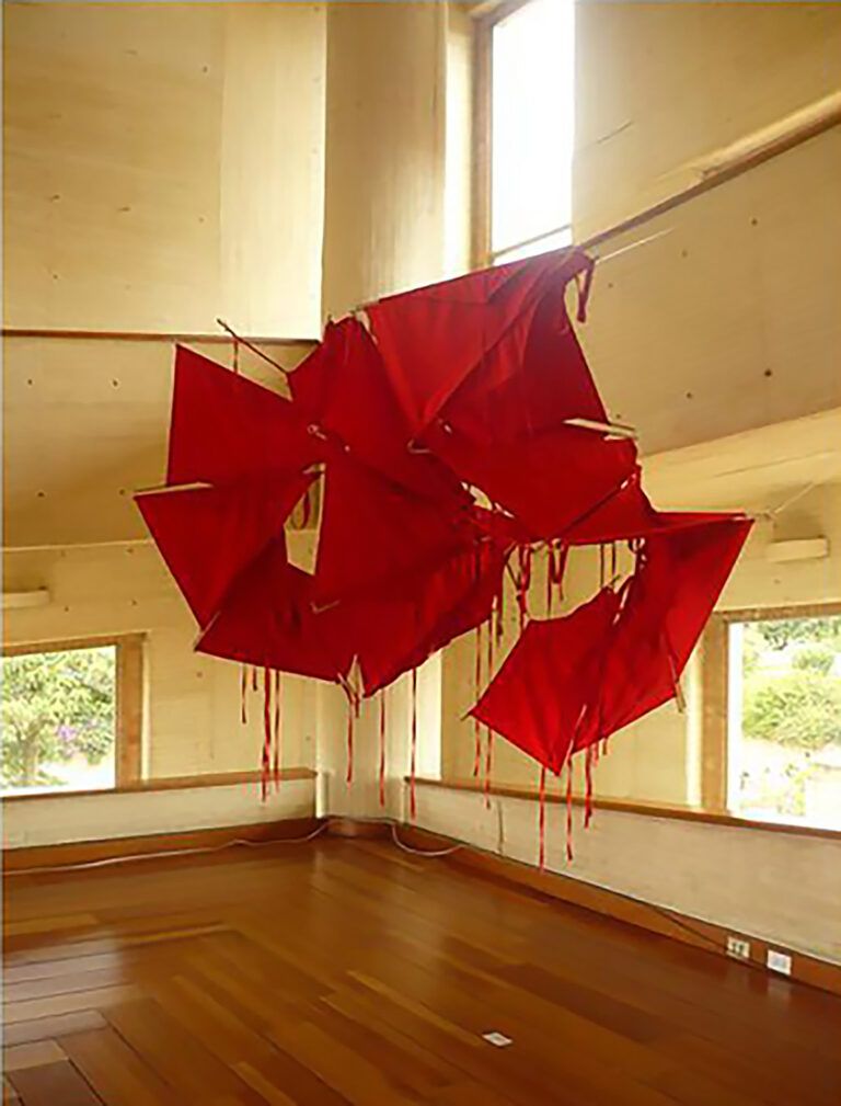 Red fabric aprons hung within an installation space interlocking and draped.