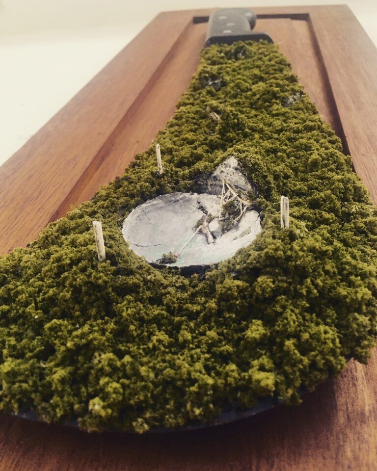 The ruins of the Arecibo Telescope and surrounding foliage recreated on the edge of a machete.